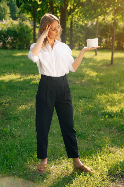 An adult fashionable woman holds a jar of no age body cream. The concept of womens skin care - Photo, image