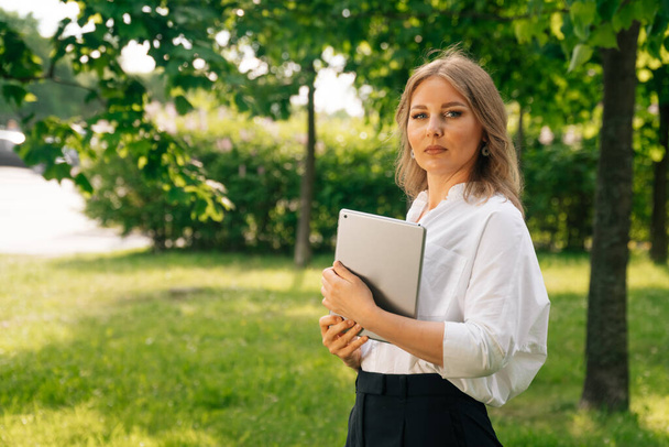 Portrait of a confident business girl looking at the camera. Businesswoman holds digital tablet in hand, stern look. - Photo, Image