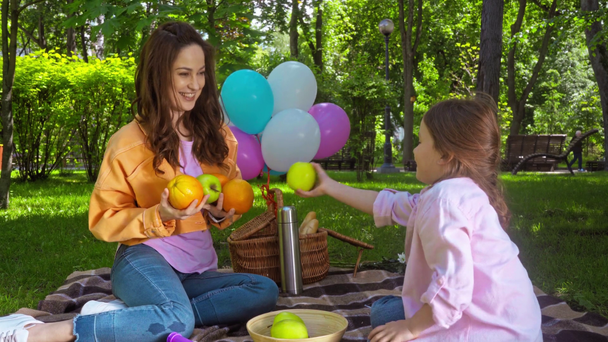 мила дочка дає фрукти веселій мамі в парку
  - Кадри, відео