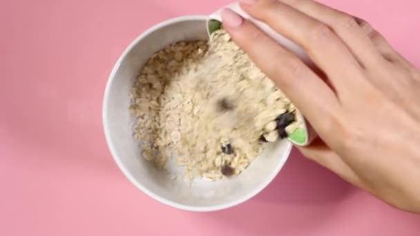 Female hands pour oatmeal into a white plate and pour yogurt from a white bottle. High quality FullHD footage - Πλάνα, βίντεο
