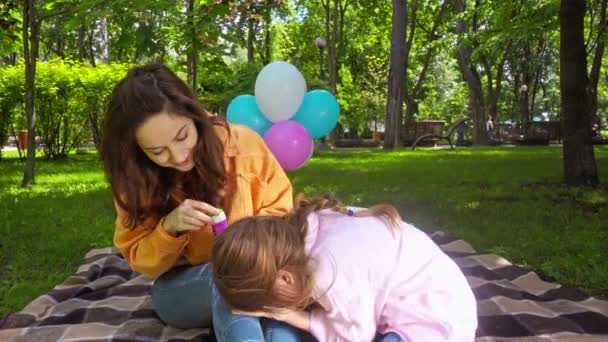 ελκυστική μητέρα φυσάει σαπουνόφουσκες κοντά χαριτωμένο κόρη για πικνίκ  - Πλάνα, βίντεο