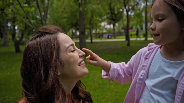 Ευτυχισμένη μητέρα αγγίζοντας τη μύτη της χαριτωμένης κόρης έξω  - Πλάνα, βίντεο