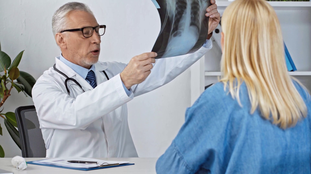 médico de meia-idade falando com o paciente e olhando para o raio-x
 - Filmagem, Vídeo
