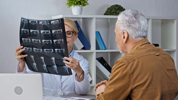 mooie volwassen arts dragen bril en kijken naar x-ray in de buurt van de man - Video
