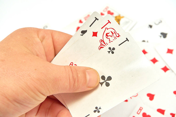 Jogando cartas em mãos em um fundo de cartas espalhadas
 - Foto, Imagem