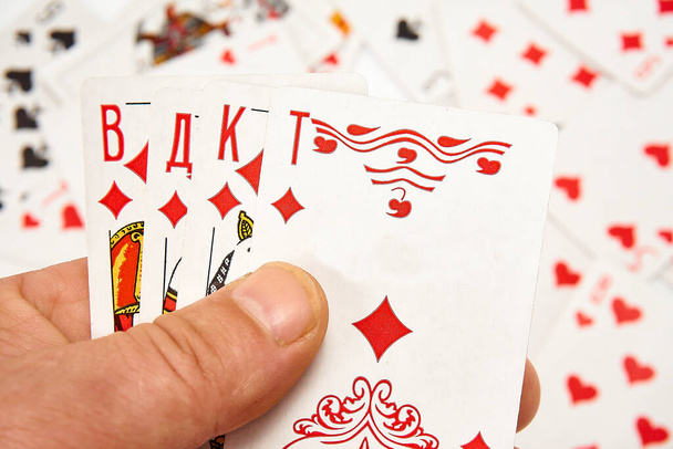 Hrací karty v rukou na pozadí roztroušených karet - Fotografie, Obrázek