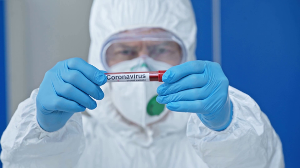 enfoque selectivo del científico masculino que sostiene el tubo de ensayo con letras del coronavirus
 - Imágenes, Vídeo