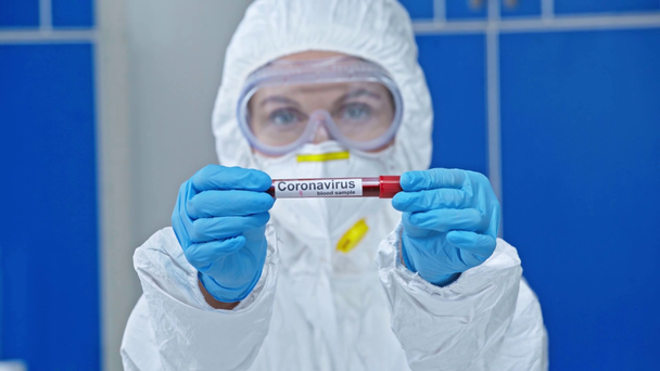 selectieve focus van wetenschapper die reageerbuis met coronavirus belettering - Video