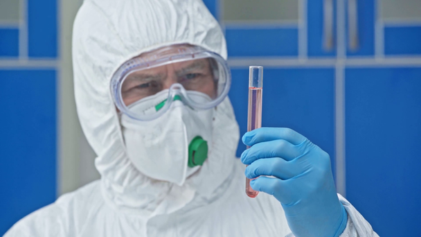 focus pull of scientist in hazmat suit holding test tube with liquid  - Footage, Video