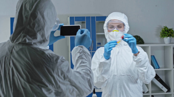 scientist taking photo of coworker with test tube  - Footage, Video