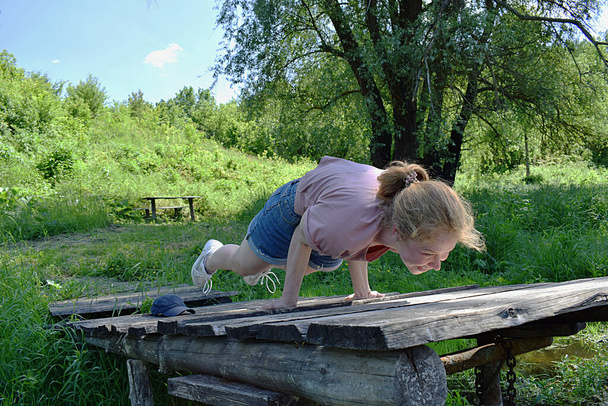 Een jonge vrouw voert een pauw pose op een rivier houten pier. - Foto, afbeelding