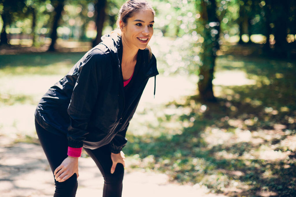 Fiatal mosolygós gyönyörű kaukázusi női futó vesz egy kis szünetet futás a természetben. - Fotó, kép