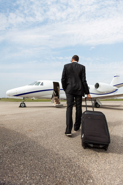 Businessman With Luggage Walking Towards Private Jet - Foto, imagen