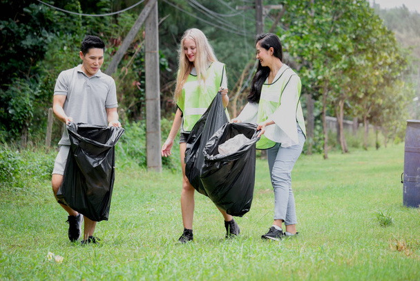 Grupa wolontariuszy zbierająca śmieci, trzymająca worek na śmieci, sprzątająca brudną, ekologiczną działalność charytatywną - Zdjęcie, obraz