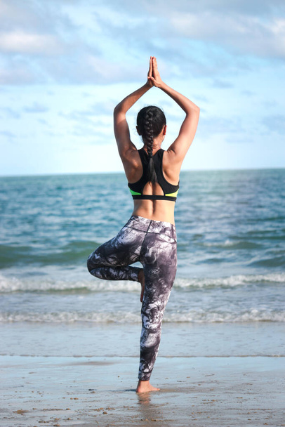 Jeune belle athlète femme faire du yoga et étirement du corps sur l'île tropicale plage d'été avec mer bleue, sport femme faire de l'exercice et de l'entraînement en plein air - Photo, image