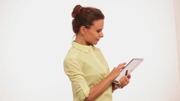 Businesswoman with holding digital tablet smiling on camera. Freelancer young woman in yellow shirt standing with tablet in her hands isolated on white. Prores 422 - Imágenes, Vídeo