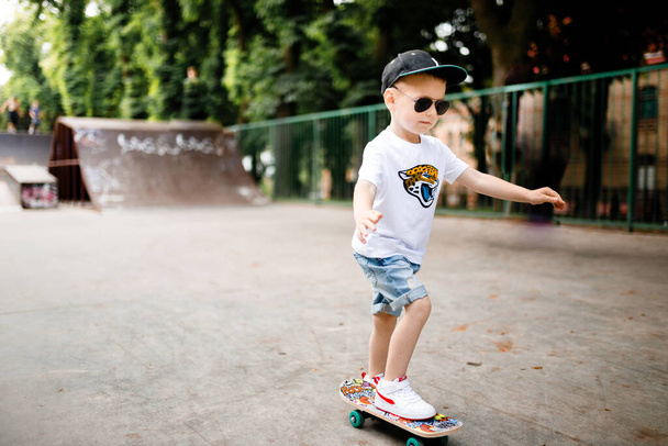 Boy with a skate in a skate park. A boy with glasses learns to skate. - Foto, Bild