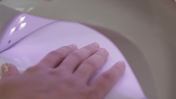 Vrouw verf nagels met rode gel polijsten alleen thuis. Uv led lamp voor het drogen van manicure. Moderne methode van werken met handen. Ultraviolet instrument, basisuitrusting. - Video