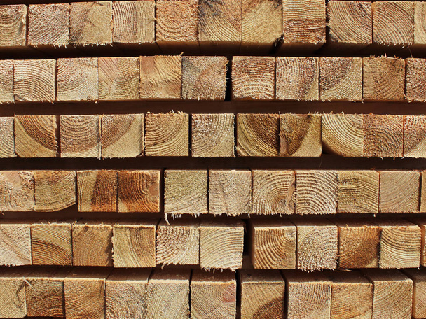аккуратный брус из хвойной древесины в пачках текстуры дерева на заднем плане
 - Фото, изображение