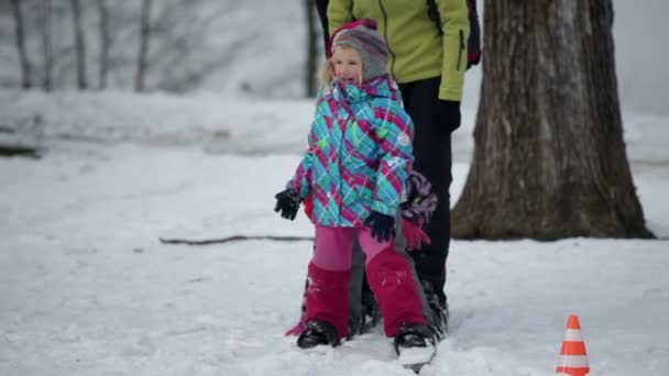kinderen glimlach en playfuly vallen na elkaar als familie op grote ski's loopt - Video