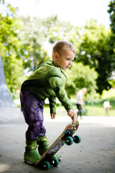 Boy with a skate in a skate park. In a superhero costume. - Foto, Imagen