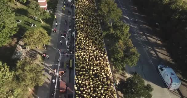 Spousta běžců se žlutými tričkami čeká maraton start ve městě Buenos Aires, procházející ulicí t uprostřed města za slunečného letního dne na Vicente Lopez Argentina s řekou v blízkosti a spoustou přírody všude kolem. - Záběry, video
