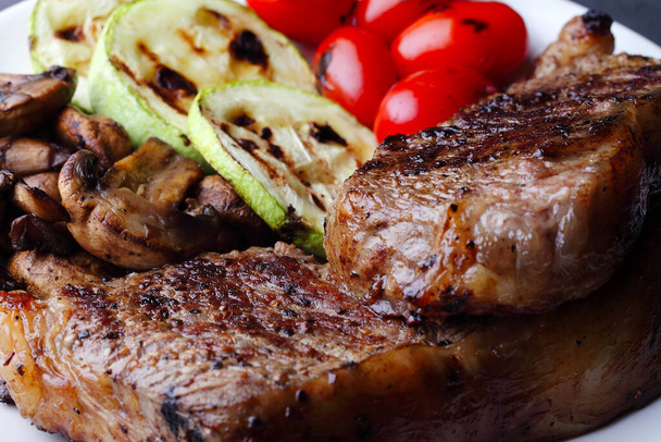 Gemarmerde biefstuk op een bord met groenten en champignons, selectieve focus, close-up - Foto, afbeelding