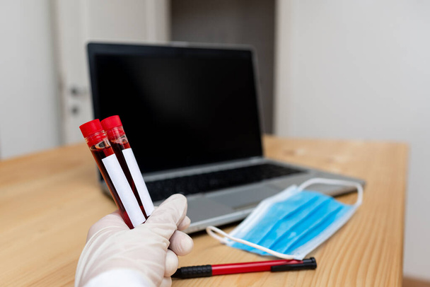 Analysant le tube à essai de laboratoire de l'échantillon de sang humain extrait avec l'ordinateur portable moderne de gadgets de dispositifs pour l'outil diagnostique de risque pour la santé - Photo, image