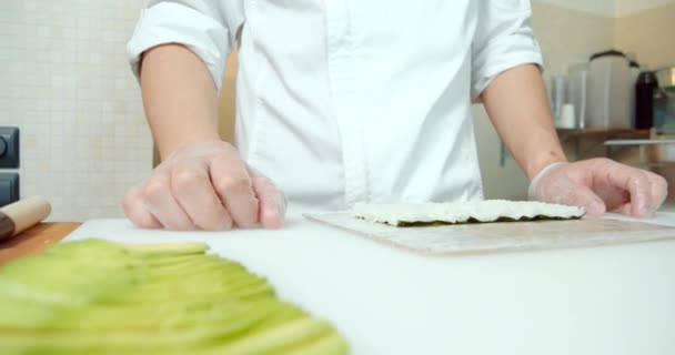 Крупним планом шеф-кухарі чоловічі руки в рукавичках готують суші рулони на кухні
. - Кадри, відео