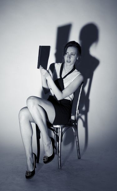 Girl sitting on a chair and reading a terrible book - Fotoğraf, Görsel