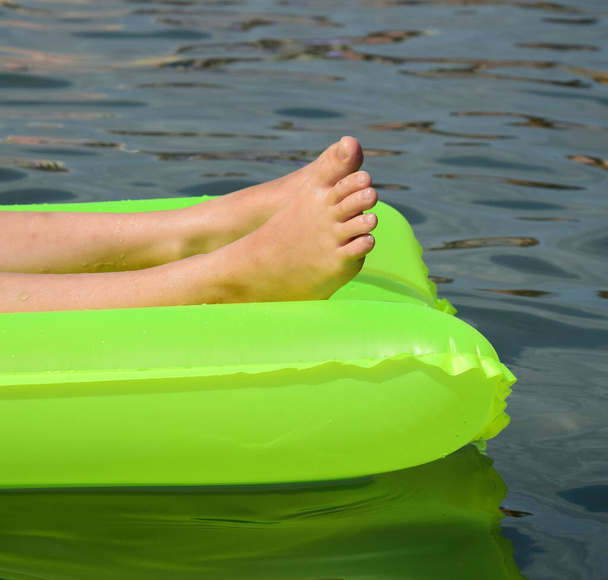 海の緑の空気マットレスの上の裸の足-クローズアップ-概念-海によるホリデーシーズン - 写真・画像