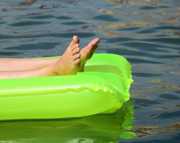 Nackte Füße auf einer grünen Luftmatratze im Meer - Nahaufnahme - Konzept - Urlaub am Meer - Foto, Bild