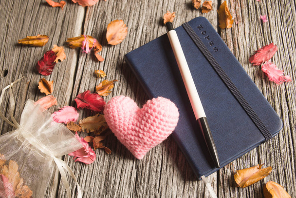 Розовое сердце и записная книжка с ручкой на фоне старого дерева
 - Фото, изображение