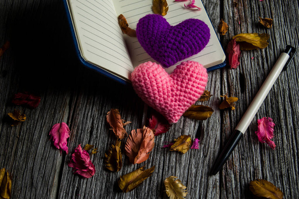 Coeur rose et coeur violet et carnet de notes avec stylo sur fond de vieux bois - Photo, image