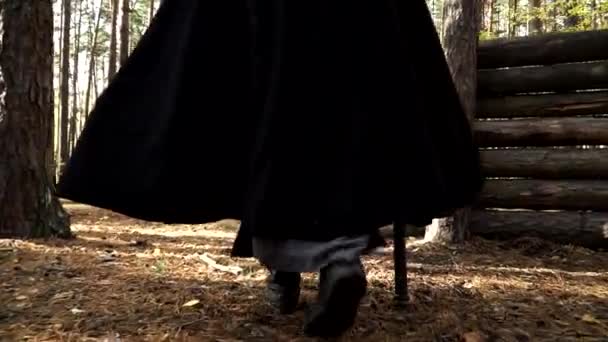 Az ember, aki Larp-ot játszik, fekete köpenyt visel és az erdőben sétál. - Felvétel, videó