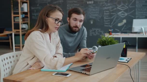 Specialists male and female sharing business ideas in office looking at laptop screen - Кадри, відео