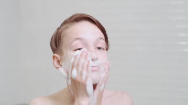 Beautiful brunette boy washes his face and dances with foam. - Felvétel, videó