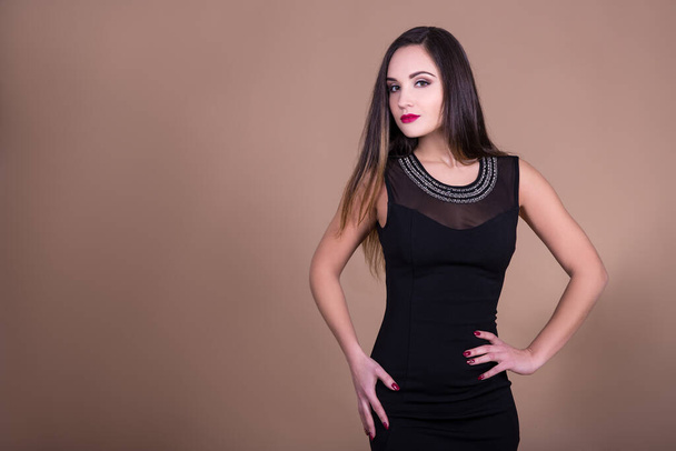 portrait of young beautiful woman in black dress with copy space over beige background - Photo, Image