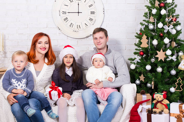 young happy family with gift boxes in front of Christmas tree - Photo, Image