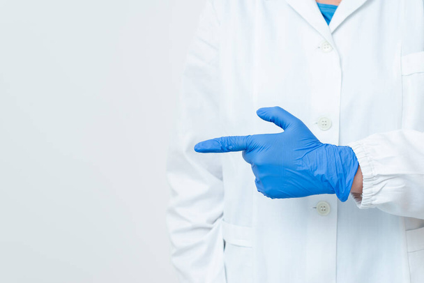 Persona que usa guantes de bata médica Máscara quirúrgica que sostiene coloridos accesorios de papel de etiqueta engomada vacía Smartphone moderno
 - Foto, imagen