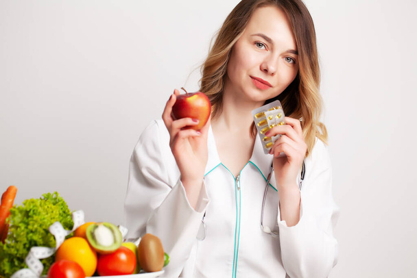 Ernährungswissenschaftlerin hält Omega-3-Fischöl-Vitamintablette und frisches Obst in ihrem Zimmer und nimmt ein Videoblog auf ihrem Handy auf - Foto, Bild