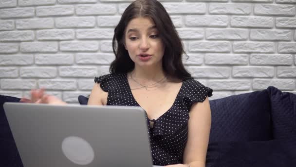 Houkutteleva nainen puhuu video chat, verkossa, käyttäen kannettavaa tietokonetta sohvalla kotona - Materiaali, video