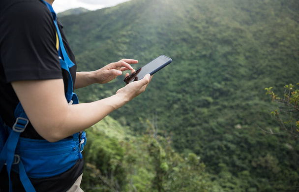 Woman hiker using smartphone on forest mountain top - Foto, afbeelding