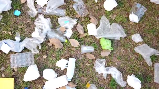 Kupa śmieci rozrzucona po trawie. Koncepcja zanieczyszczenia środowiska. Wideo 4K - Materiał filmowy, wideo