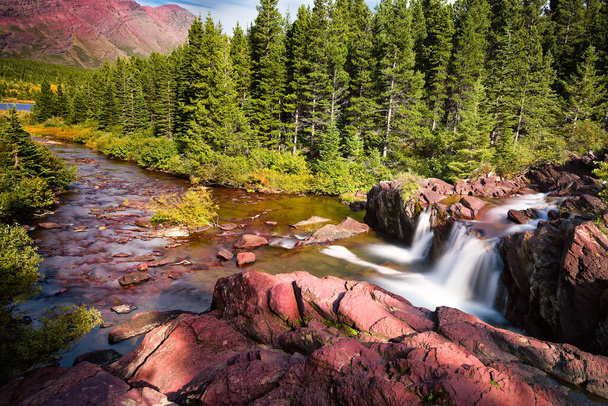 赤い岩と滝はモンタナ州の東氷河国立公園にあります。 - 写真・画像