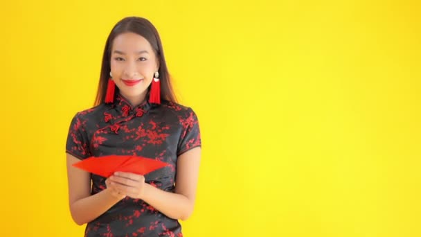 close-up footage of beautiful young Asian woman in traditional chinese dress with handheld fan isolated on yellow - Felvétel, videó