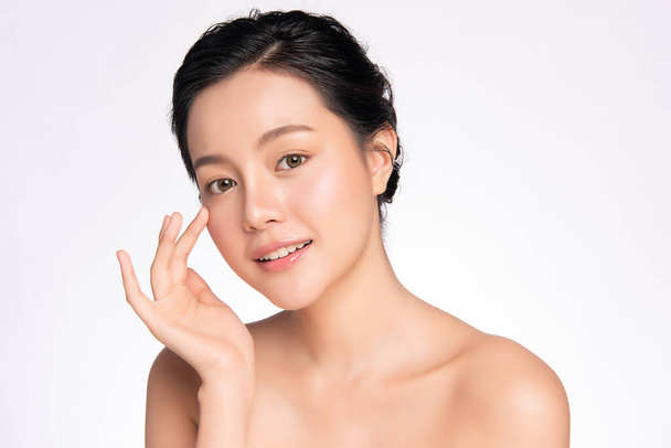 Kaunis nuori aasialainen nainen koskettaa hänen puhtaat kasvonsa tuoreella terveellä iholla, eristetty valkoisella taustalla, kauneus kosmetiikka ja kasvohoito käsite, - Valokuva, kuva