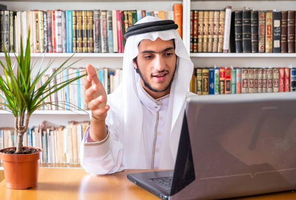 Homem muçulmano árabe usando seu laptop para fazer seminários on-line
 - Foto, Imagem