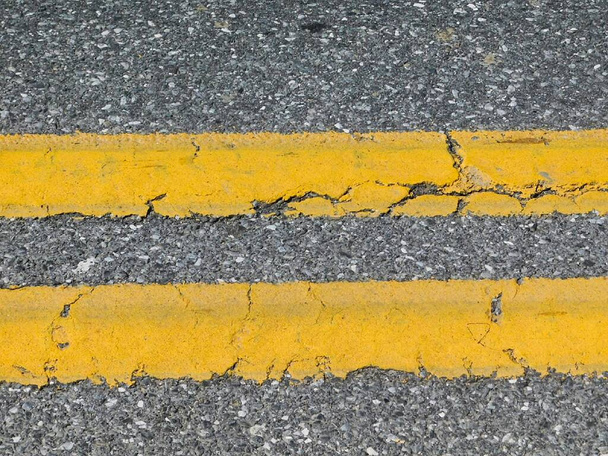 Close-up van horizontale effen dubbele gele lijnen in het midden van de weg - Foto, afbeelding