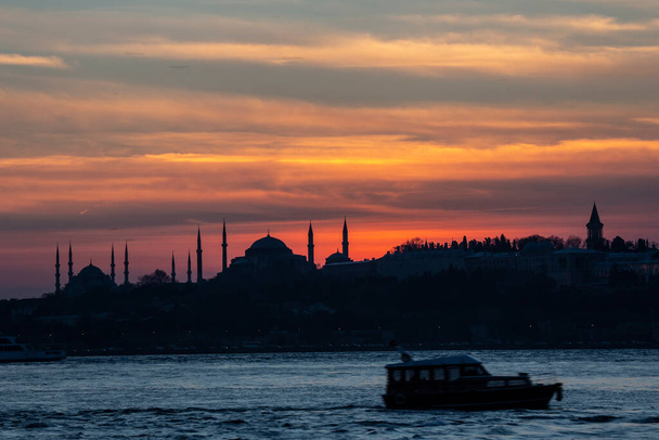 Zon onder boven de Blauwe Moskee met Hagia Sophia in silhouet op de Bosporus Istanbul. - Foto, afbeelding